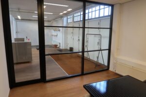 Modern kantoorinterieur aan het Gedempt Hamerkanaal met glazen scheidingswand en houten vloer.